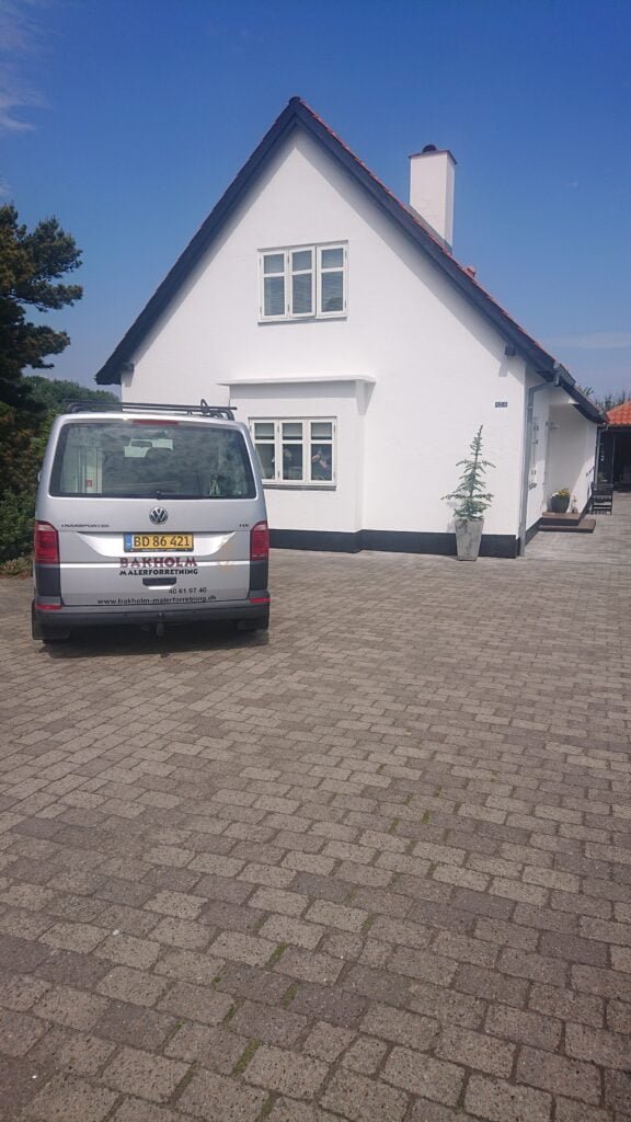 Hvidt hus med bil foran indkørsel