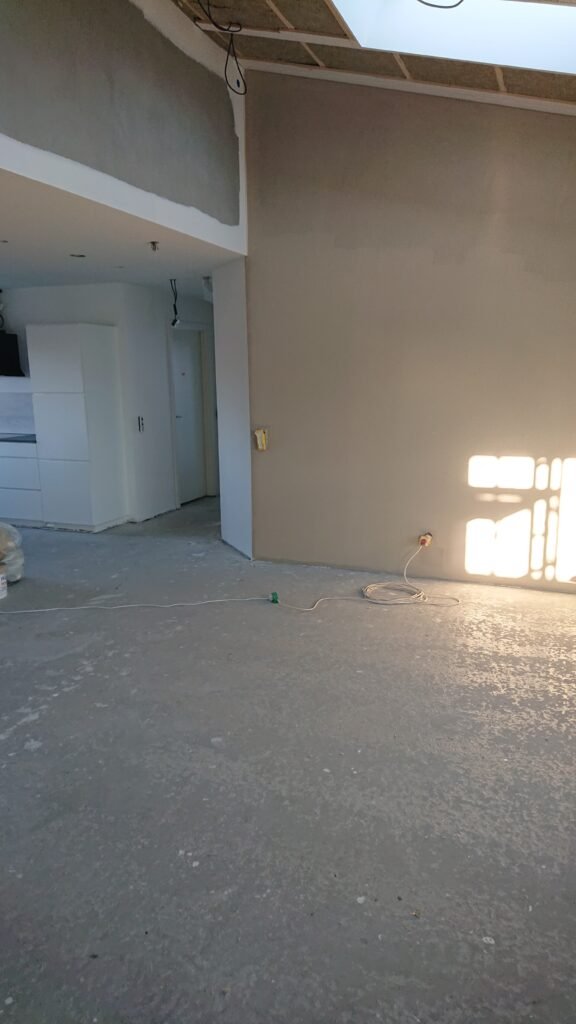 Nyrenoveret rum med gråt gulv og hvidt køkken