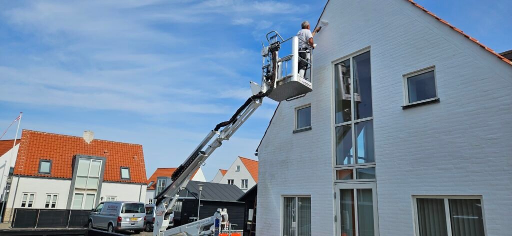 Mand maler husfacade fra lift