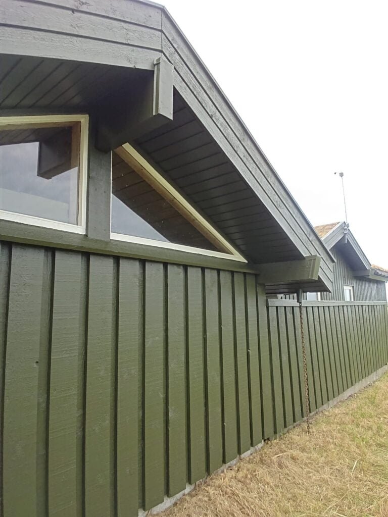 Grønt træhus med trekantede vinduer og skråt tag