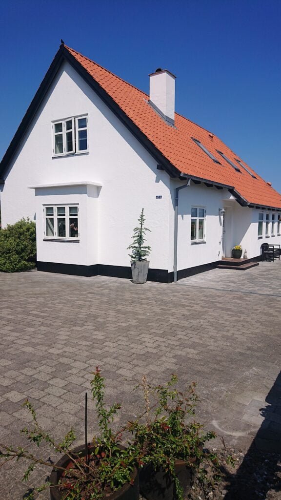 Hvidt hus med rødt tag under blå himmel